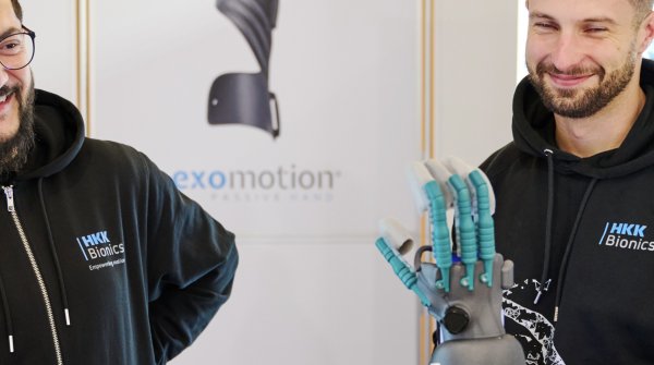 Vier Personen stehen um eine mechanische Hand auf der ISPO