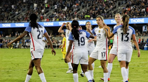 Frauen spielen im Stadion Fußball und klatschen sich ab