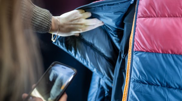 Person schaut sich bunte Outdoor-Jacke auf der ISPO 2024 an