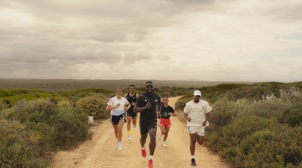Eine Gruppe an Läufern joggt durch die Natur.