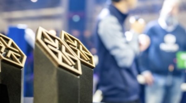 Award Trophäe im Fokus mit Gewinner auf der Bühne im Hintergrund