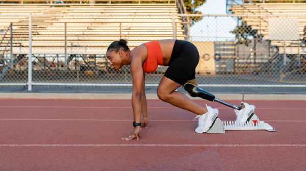 Une femme sportive avec une prothèse de jambe au départ d'une piste d'athlétisme