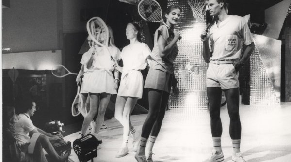 Models führen Tennisbekleidung auf einer Bühne vor.