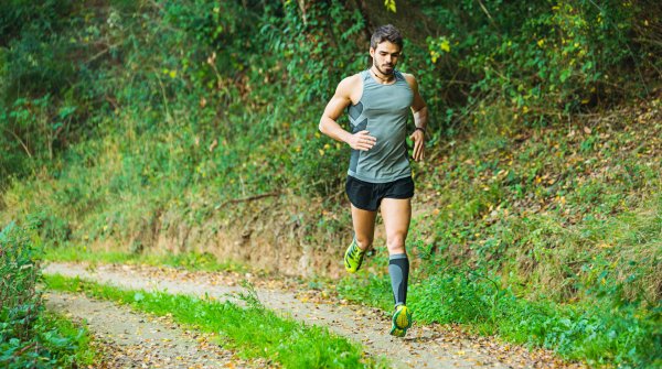 Ein Jogger auf einem Waldweg.