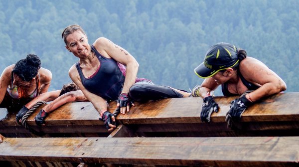 Three women climbing an obstacle