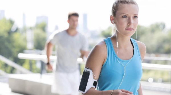 Frau joggt mit Handy am Arm