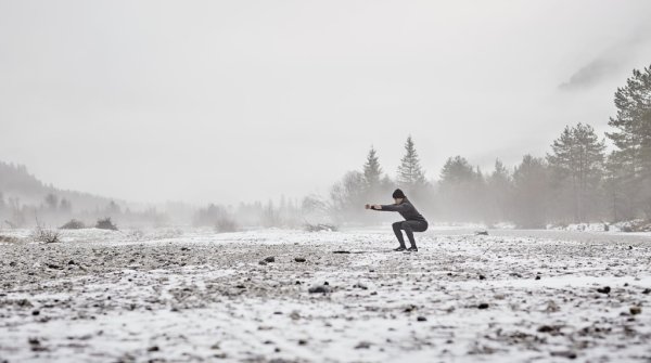 Frau macht Übungen auf einem schneebedeckten Feld.