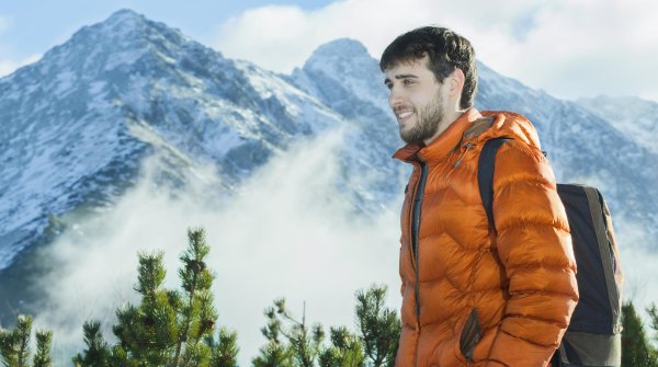 Mann mit Daunenjacke vor Bergpanorama