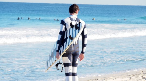 With the strips and shapes on the wetsuit and surfboard, the shark is less likely to have the surfer “for lunch.”