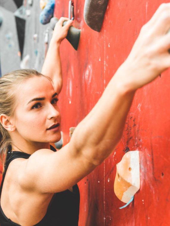 Frau klettert an einer Boulderwand