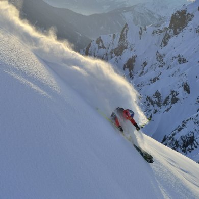 Ein Wintersportler pflügt durch den Schnee an einem steilen Berghang