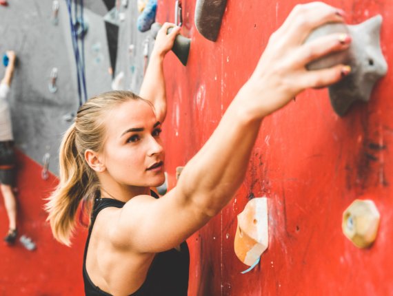 Frau klettert an einer Boulderwand