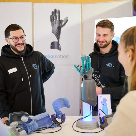 A group of people stand around a mechanical hand