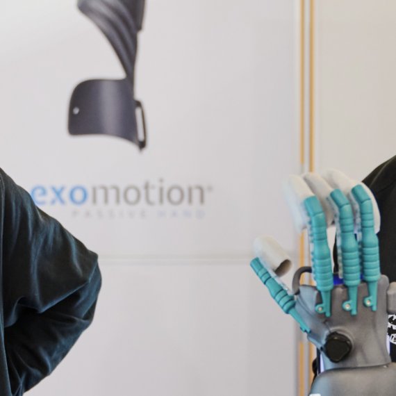 Vier Personen stehen um eine mechanische Hand auf der ISPO