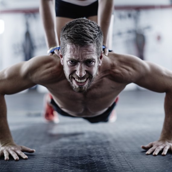 A man with a very strained expression on his face doing sports with sore muscles.