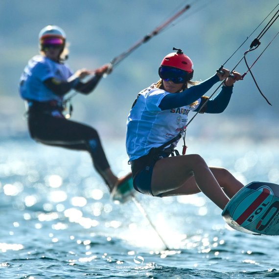 Two kitefoilers float over the water. 
