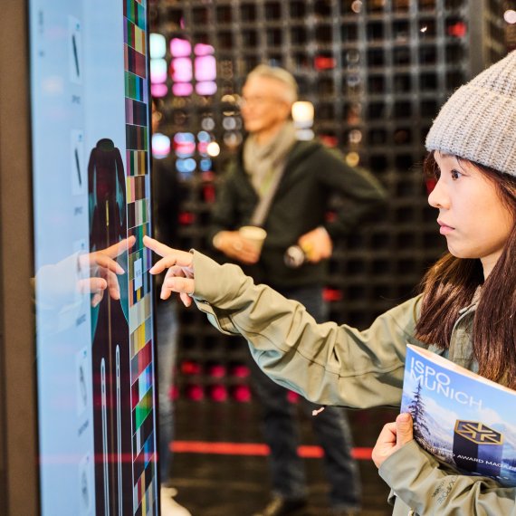 Frau auf der ISPO 2024 tippt auf Bildschirm
