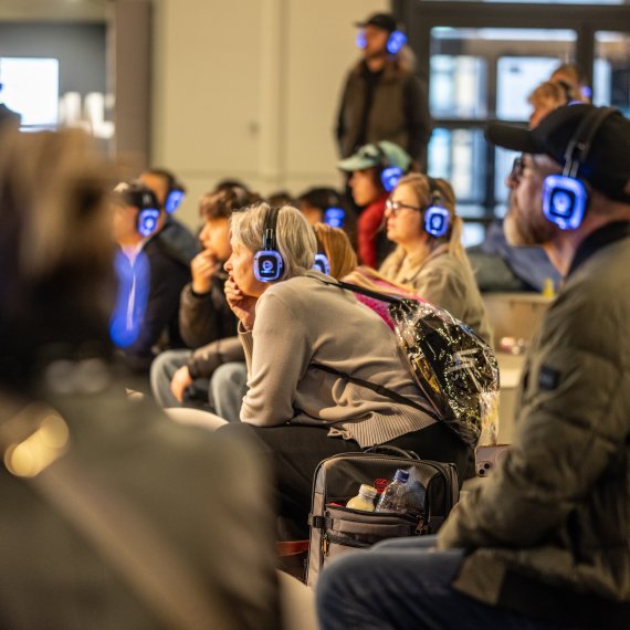 Seated people with headphones during a talk at ISPO 2024
