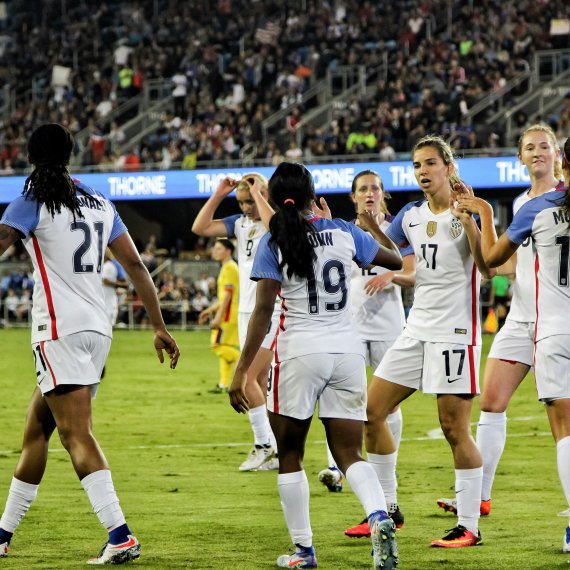 Women play soccer in the stadium and high-five each other