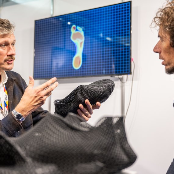 Person looks at colorful outdoor jacket at ISPO 2024
