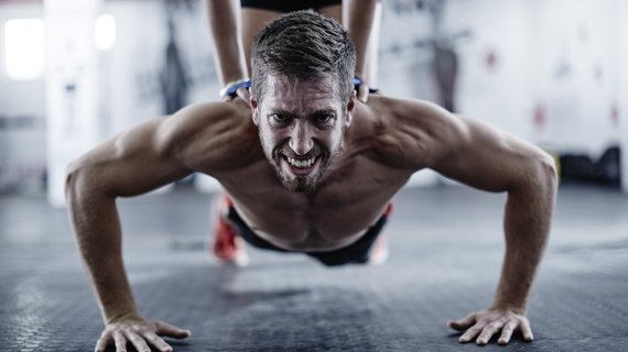 A man with a very strained expression on his face doing sports with sore muscles.