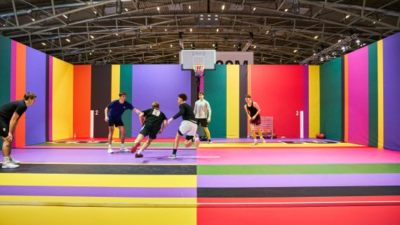 Junge Leute spielen auf buntem Basketballplatz