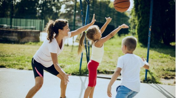 Mutter spielt mit ihren zwei Kindern Basketball