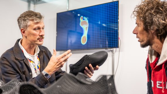 Une personne regarde une veste d'extérieur colorée à l'ISPO 2024