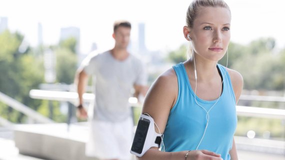 Frau joggt mit Handy am Arm