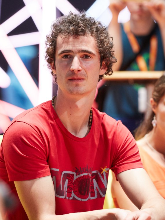 Adam Ondra sitzt zwischen Menschen